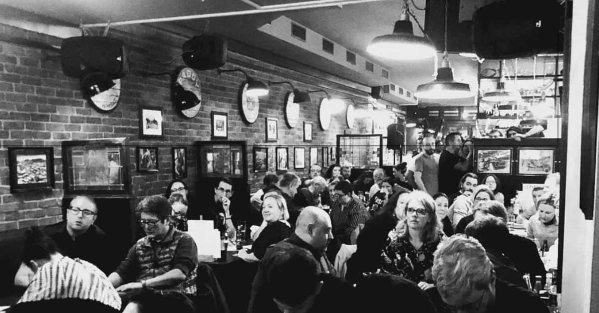 A black and white photo of a bustling restaurant during an English-language pub quiz in Haarlem.